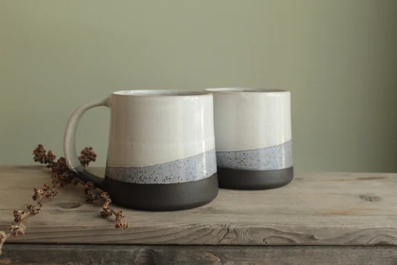 Modern minimalist porcelain mugs with three-tone design on rustic wood.